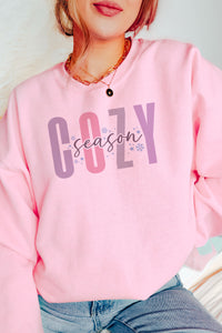 a woman wearing a pink sweatshirt with the word cozy on it