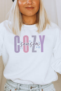 a woman wearing a white sweatshirt with the word cozy on it