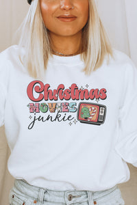 a woman wearing a white christmas sweatshirt and a black beanie