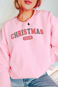 a woman wearing a pink christmas crew sweatshirt